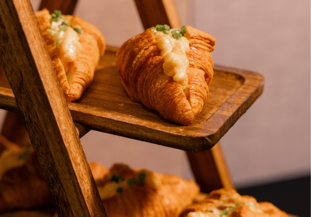 Freshly prepared egg mayonnaise croissant sandwiches displayed on a rustic wooden serving stand at ibis Singapore on Bencoolen