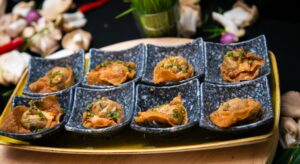 Golden crispy dumplings garnished with fresh herbs, served in elegant stoneware dishes on a wooden platter.