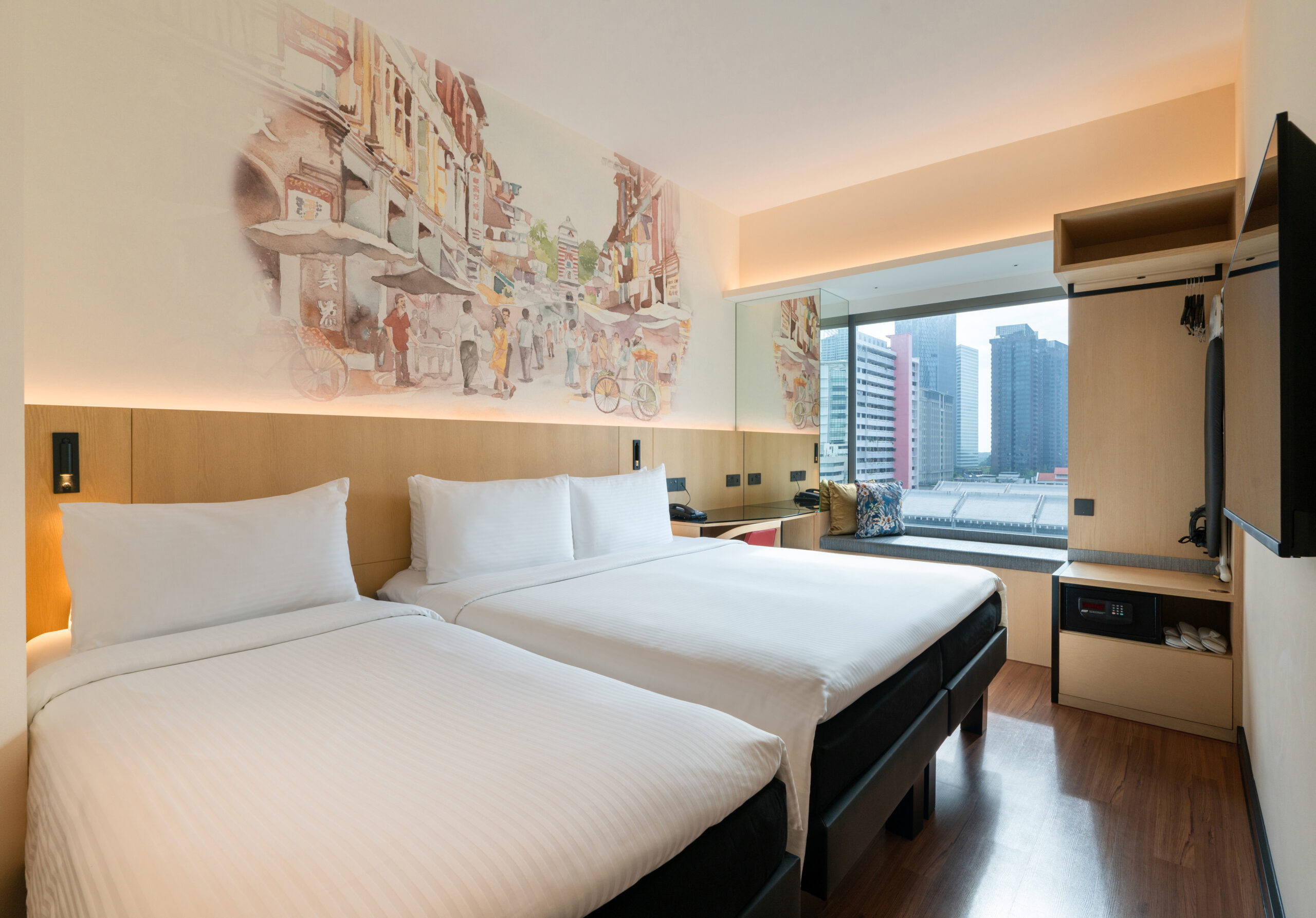 Hotel room featuring 1 Queen bed and 1 single bed with a decorative headboard mural illustrating a olden day Singapore street at the background, a study table, and a bay window offering natural light.