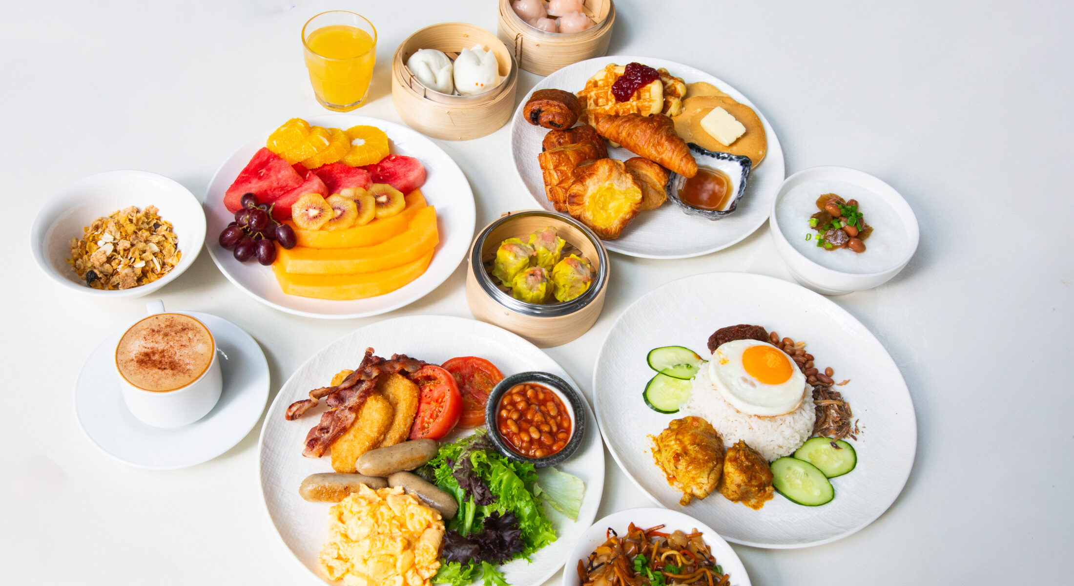 Buffet spread with nasi lemak, dim sum, eggs, sausages, cereals, fruits, and coffee.