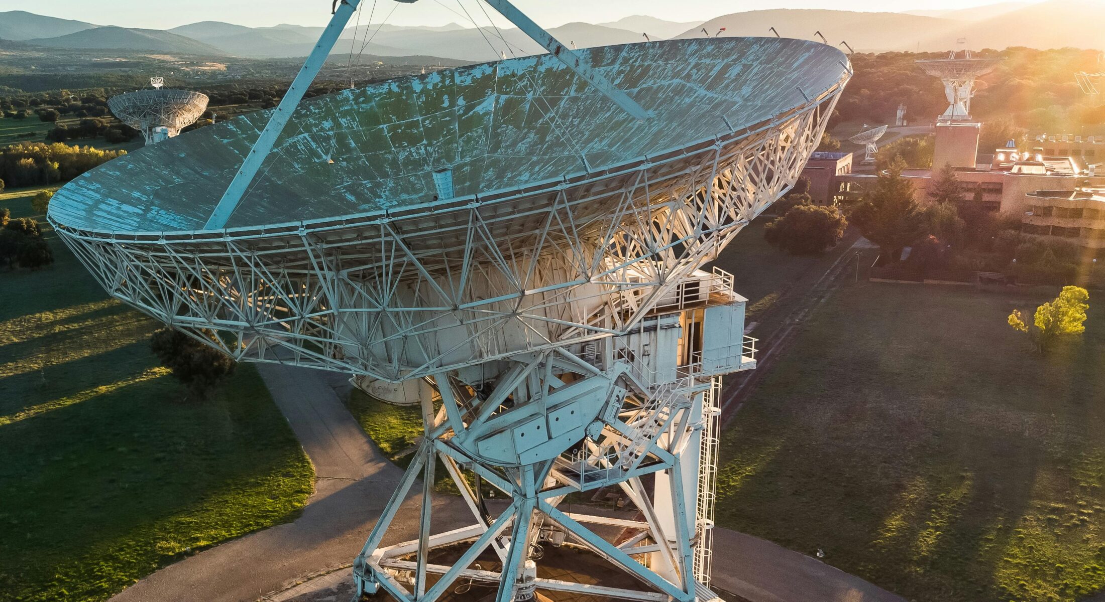 Large satellite communication dish at sunset in a rural landscape, symbolising global connectivity and advanced communications technology.