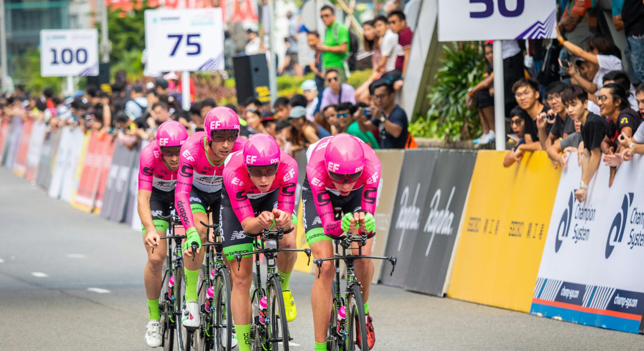 Cyclists racing in a professional road cycling event in Singapore with spectators lining the route during a major sports competition.