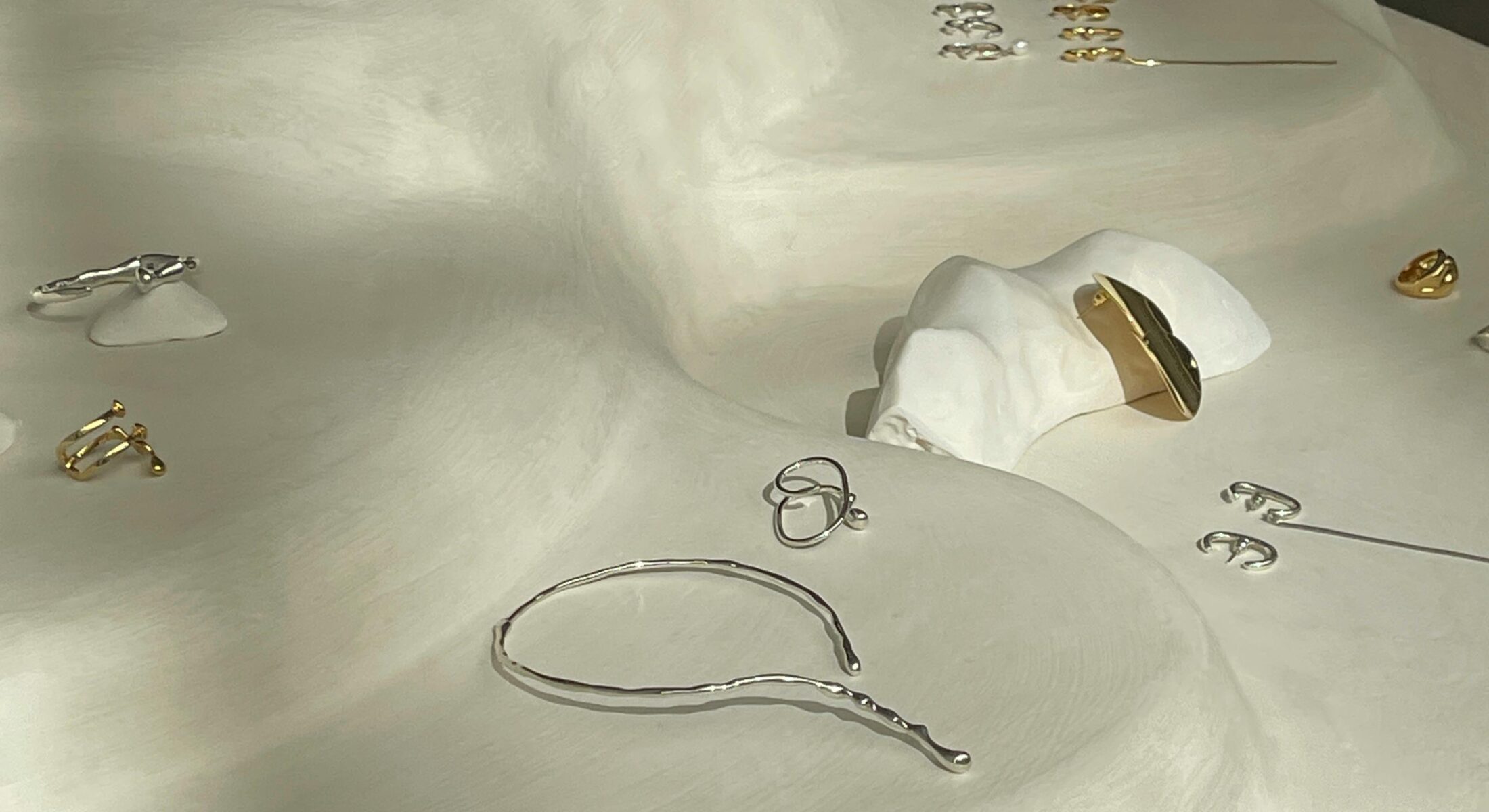 Contemporary jewellery pieces displayed on sculptural white plinths at a design exhibition