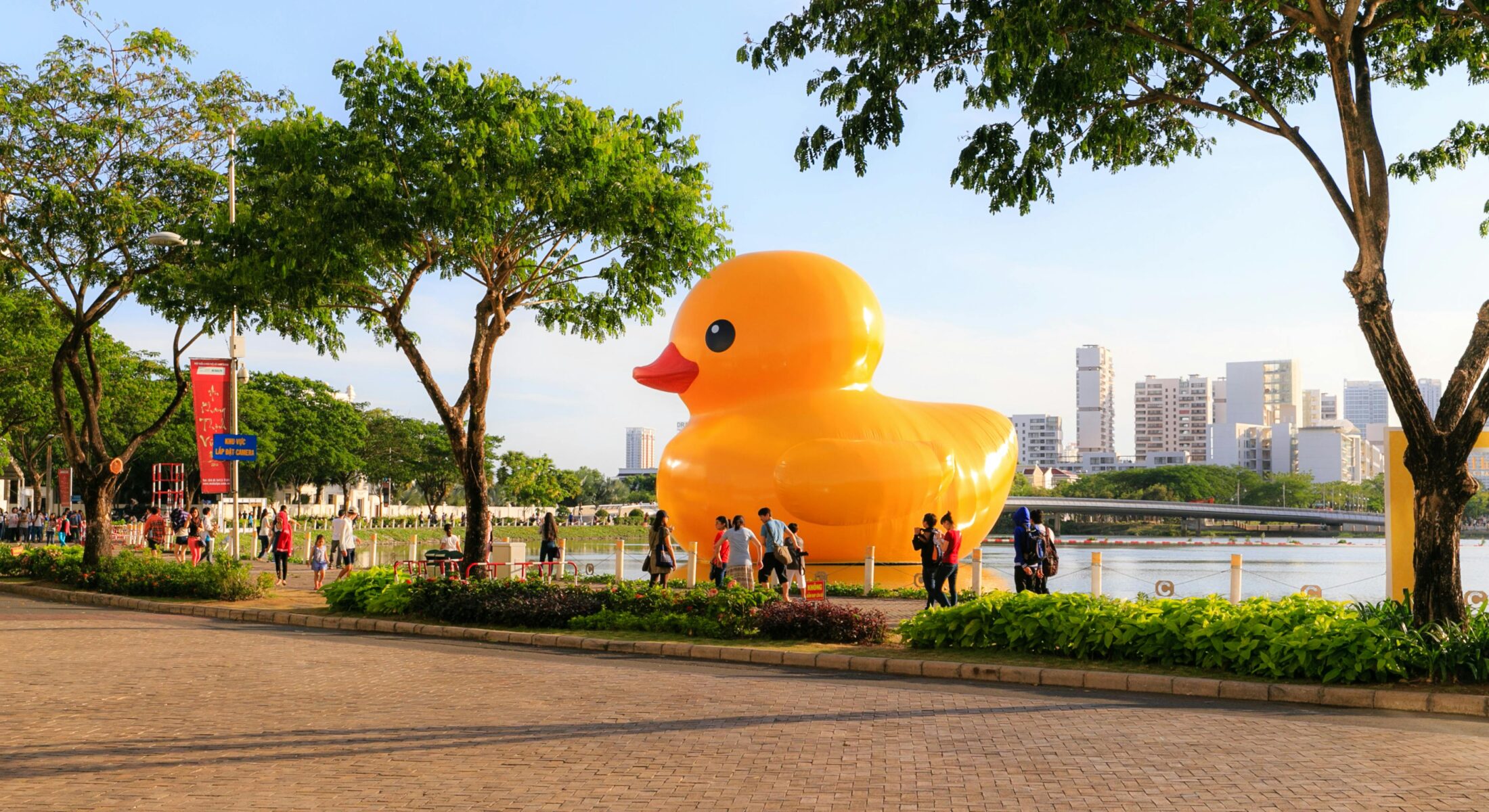 Visitors walking along the waterfront in Singapore with a giant inflatable yellow duck art installation during a public outdoor event.