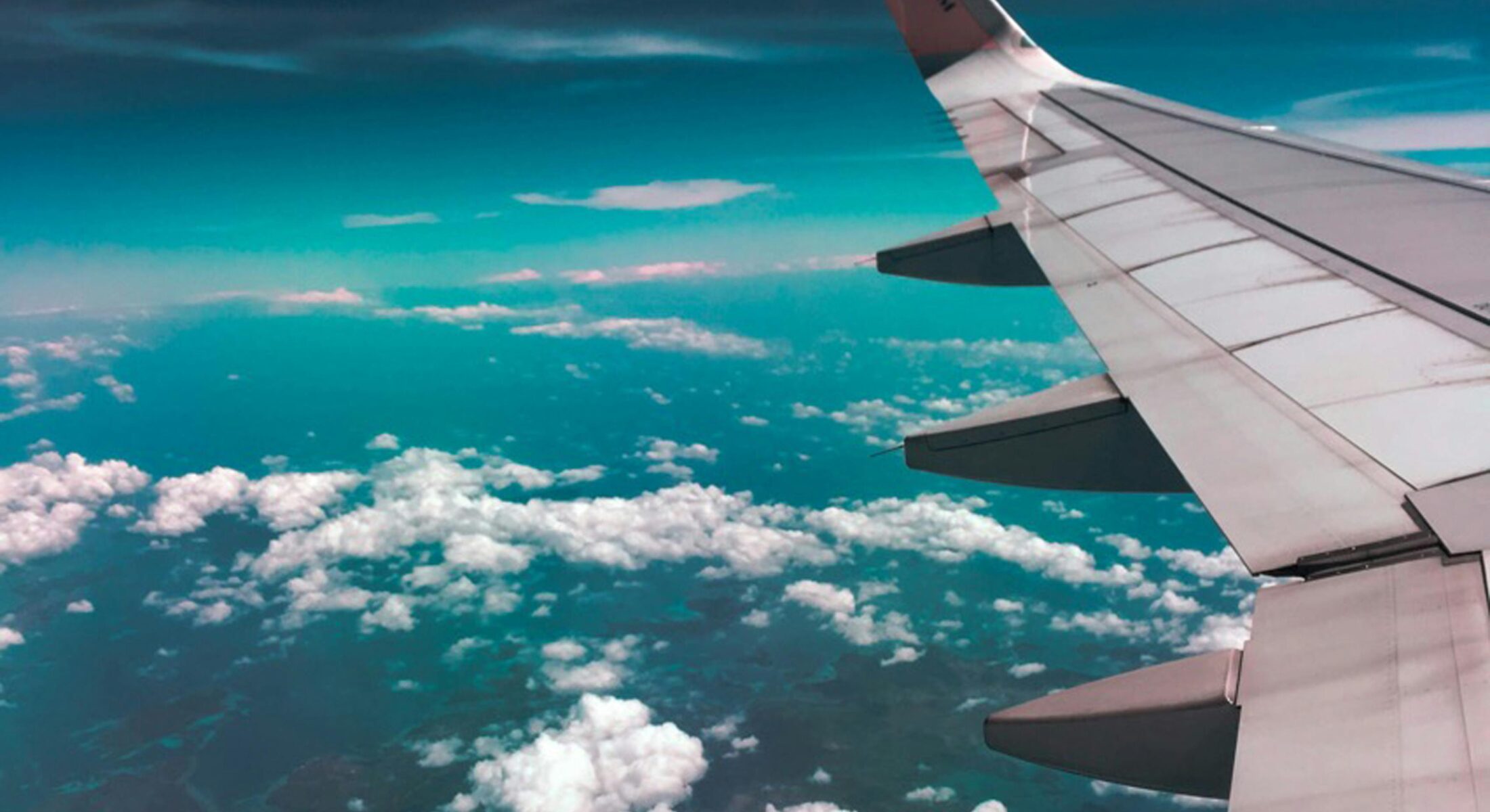 View of airplane wing above clouds en route to Singapore for Aviation Festival Asia 2026 at Suntec