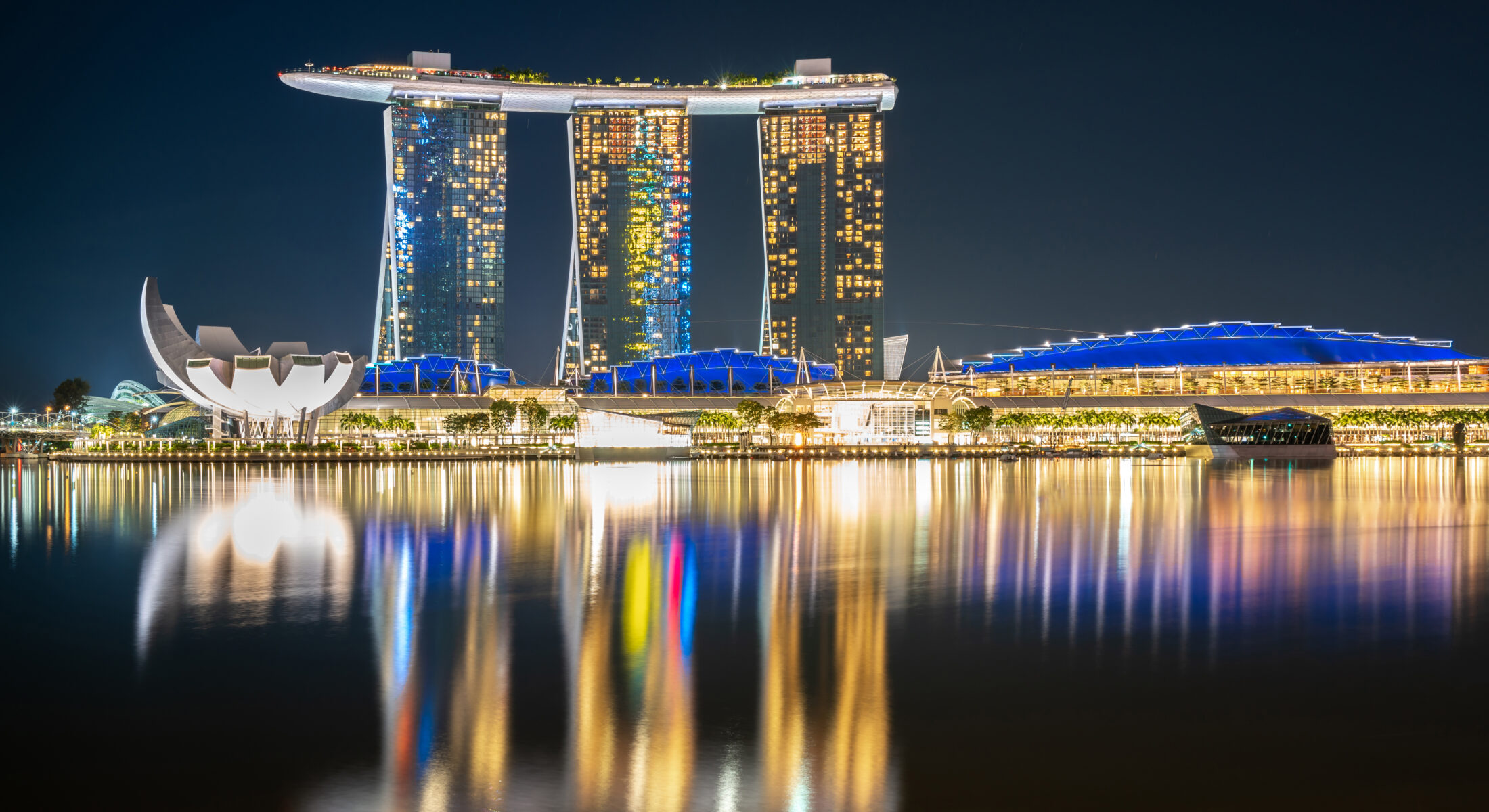 Night view of Marina Bay Sands Expo at Marina Bay, Singapore, featuring the iconic skyline reflected across the waterfront.