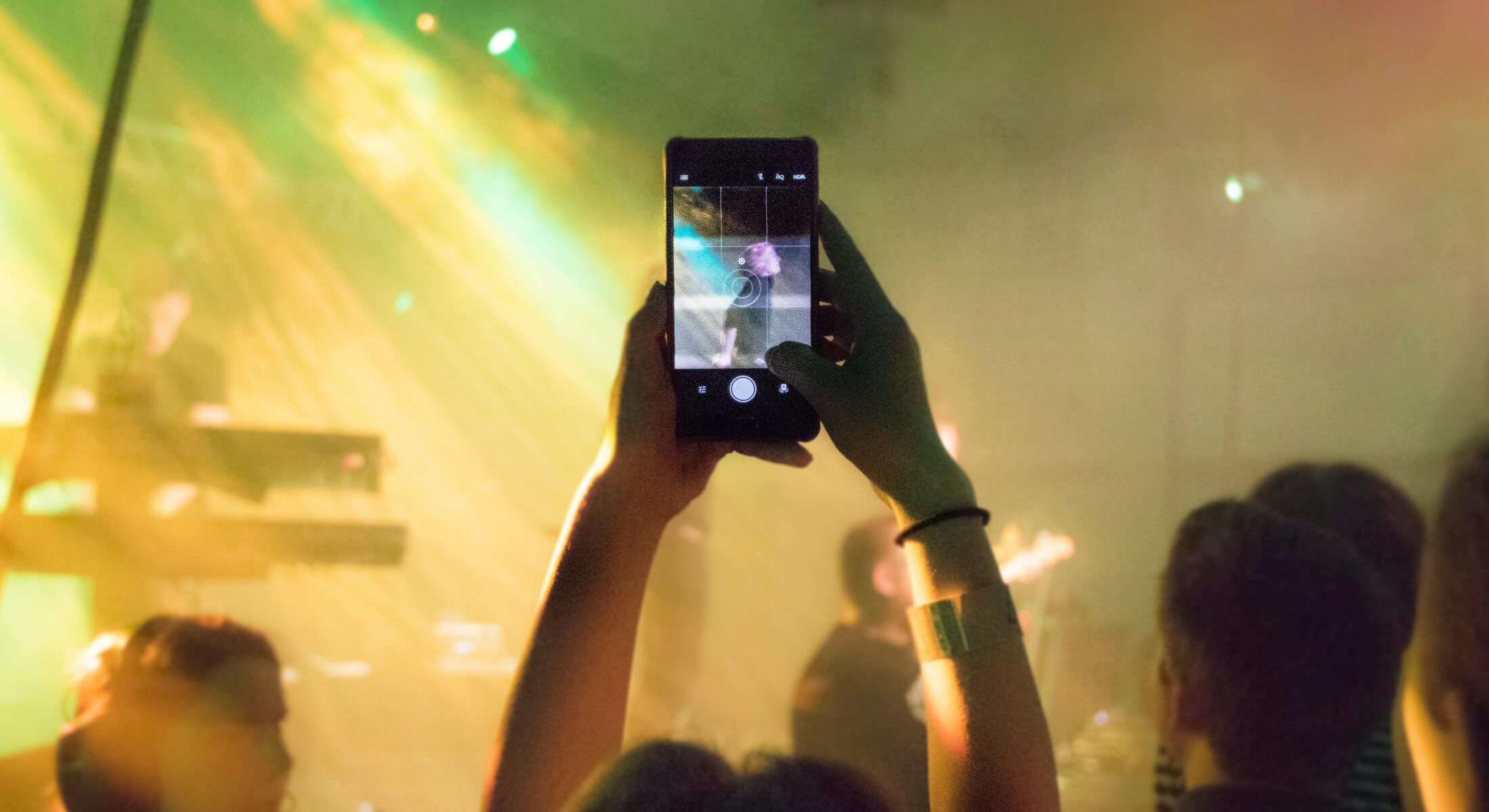 Concert crowd capturing a live performance on a smartphone with colourful stage lights at a music event in Singapore