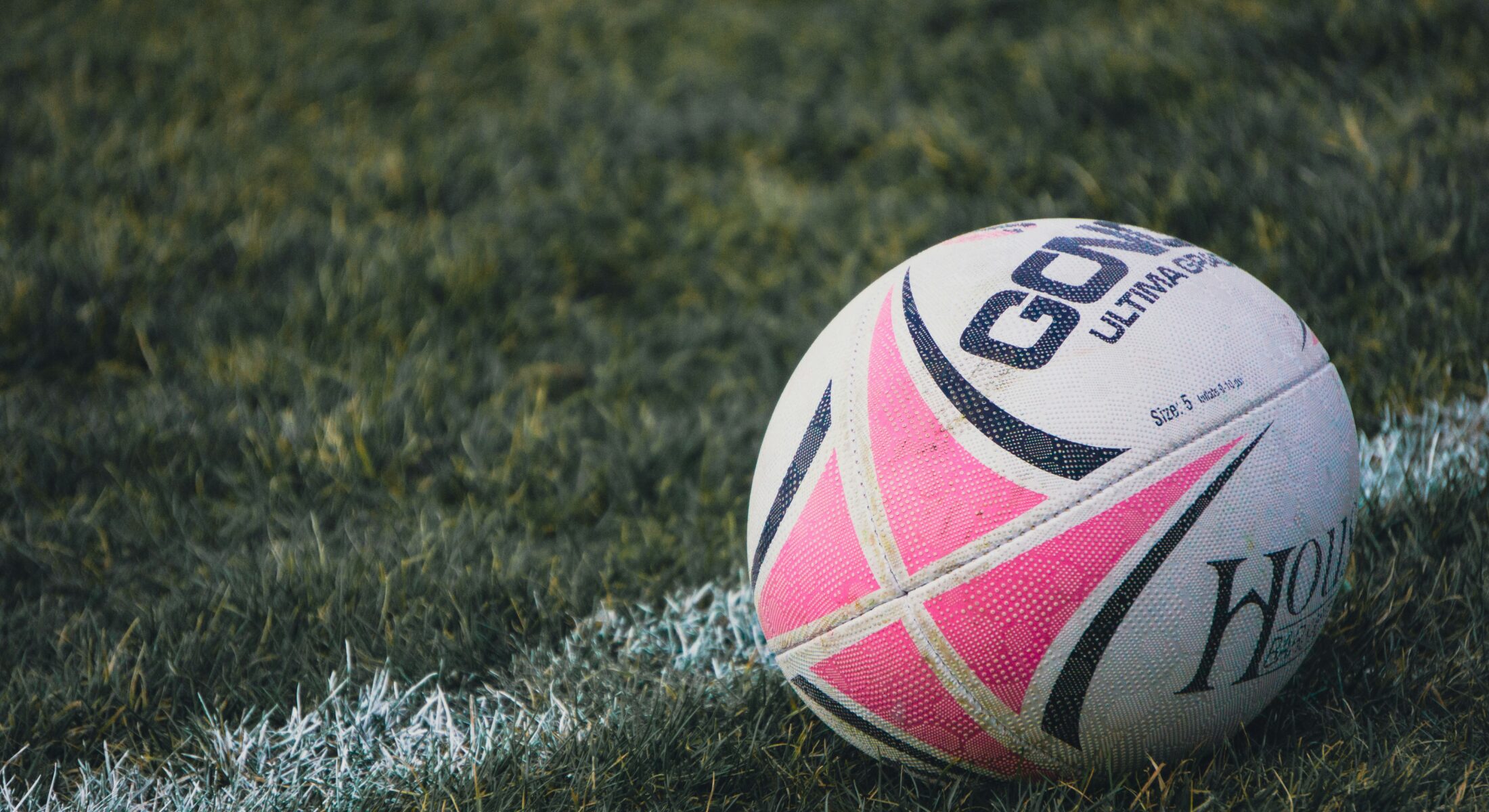 Rugby ball resting on a grass pitch, symbolising an international rugby sevens tournament in Singapore.
