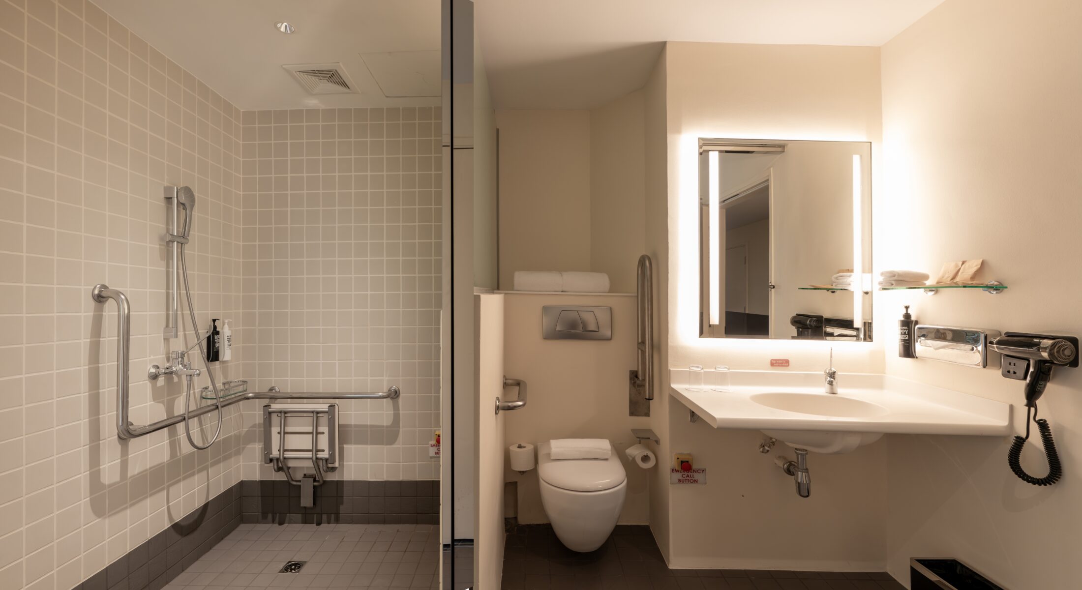 Accessible bathroom at ibis Singapore on Bencoolen featuring a roll-in shower, support grab bars, foldable shower seat, lowered sink area, and barrier-free design.